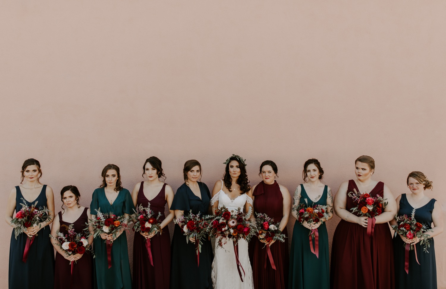 Bridal party striking a pose against a pastel pink wall