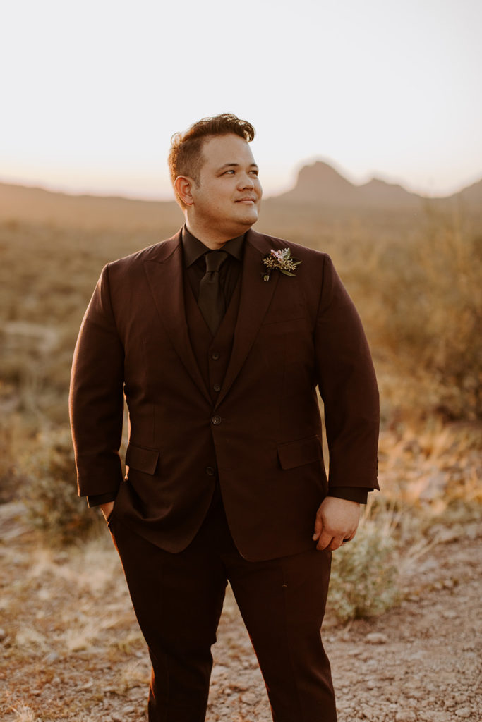 Groom wearing a dark suit and boutonniere in the desert
