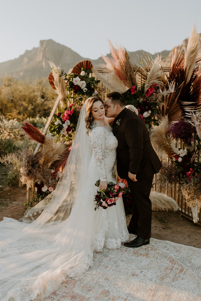 bride and groom sunset portraits in front of their ceremony backdrop in the desert 