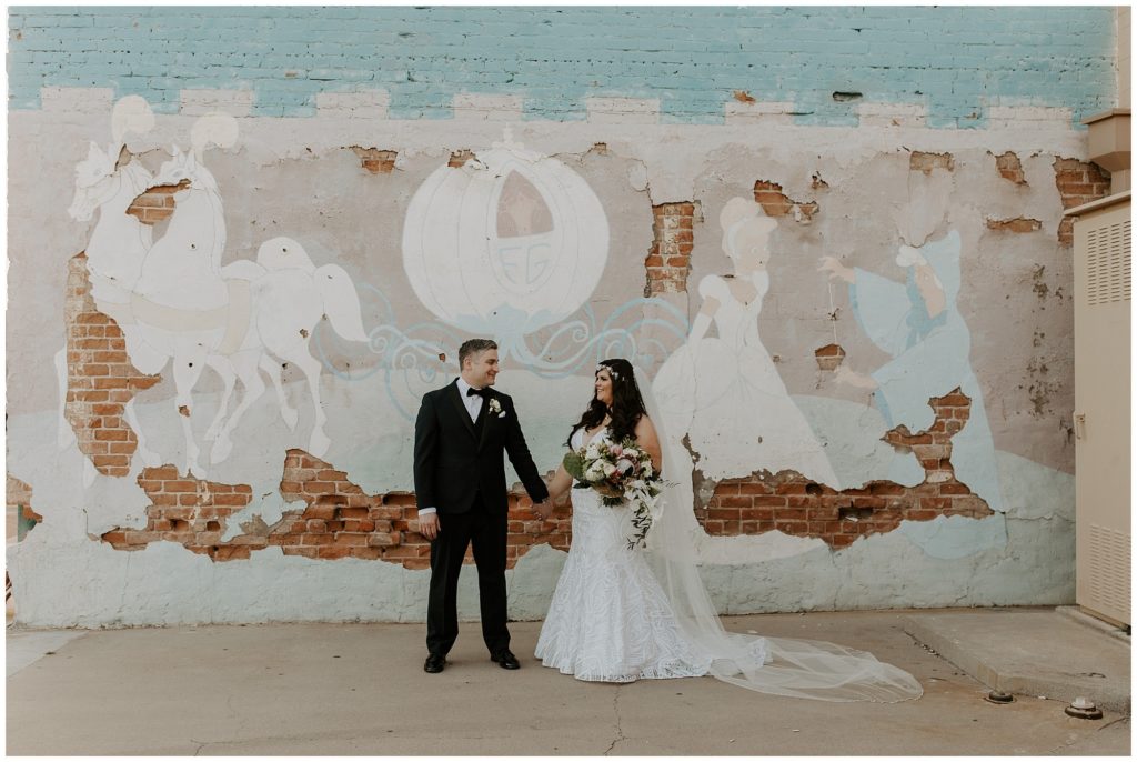 Bride and groom posing in front of a colorful wall in downtown Mesa on their wedding day