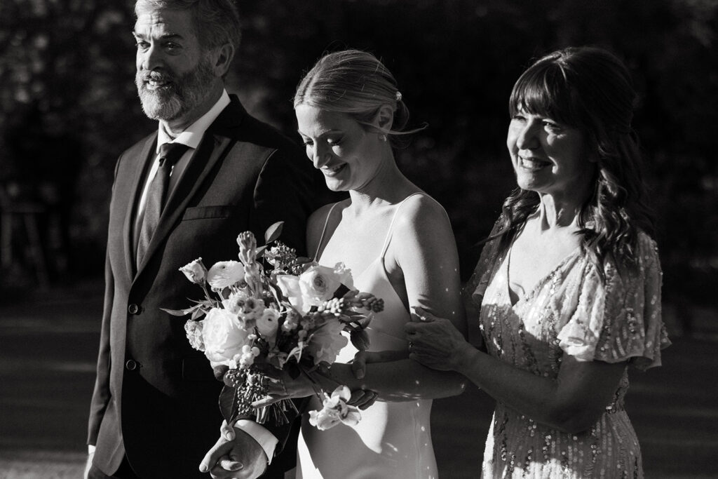 black and white photo captures a bride smiling as she walks down the aisle at her Scottsdale wedding