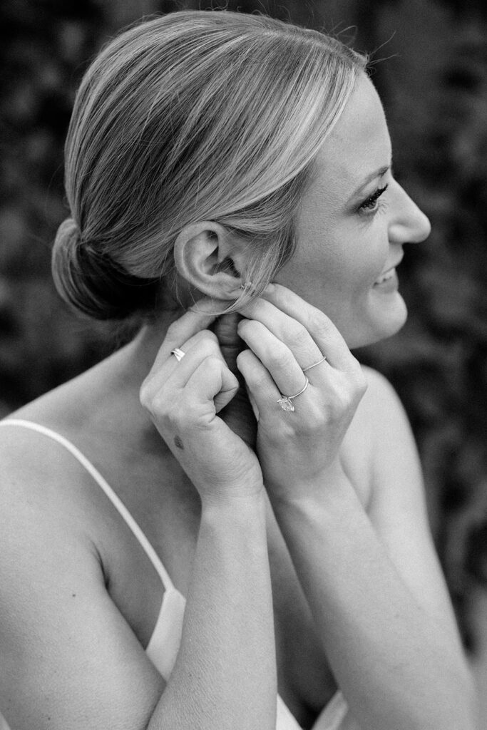 Stunning bride puts on her earrings as the final touch to her classic bridal look
